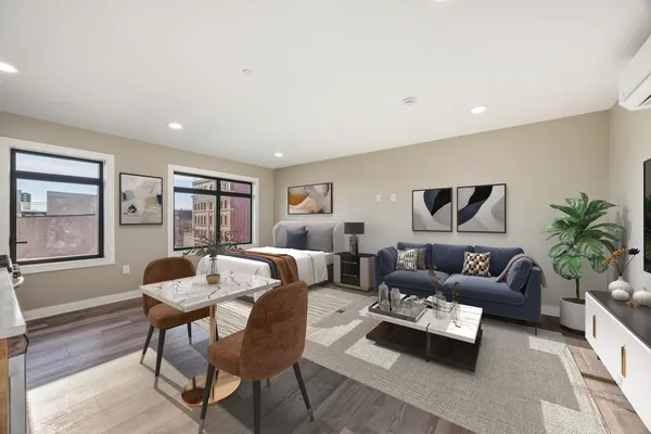 a living room with stainless steel appliances furniture a rug and a kitchen view