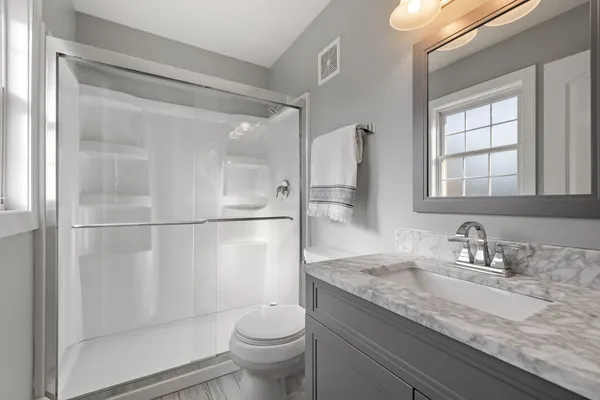 a bathroom with a granite countertop sink a toilet and shower