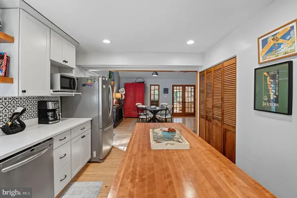 a kitchen with stainless steel appliances kitchen island granite countertop a stove a sink dishwasher and a refrigerator with wooden floor