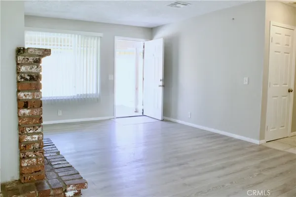 an empty room with wooden floor fireplace and windows