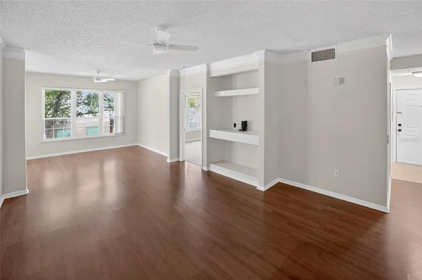 a view of an empty room with wooden floor and a window