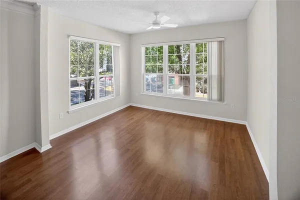 a view of an empty room with wooden floor and a window