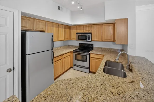 a kitchen with granite countertop a refrigerator sink stove microwave and cabinets