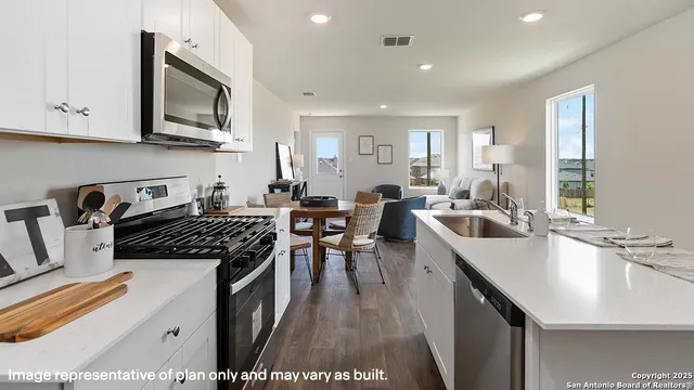 a kitchen with granite countertop a sink a counter space appliances and cabinets