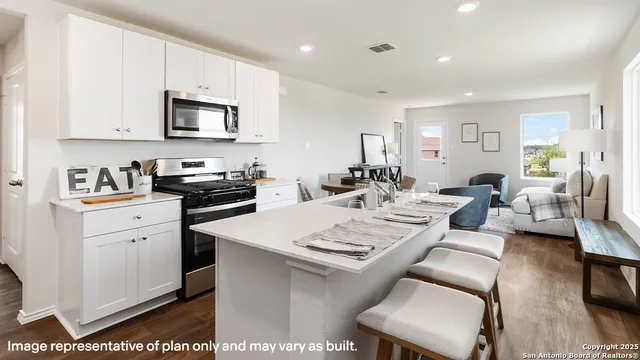 a open kitchen with stainless steel appliances kitchen island granite countertop a sink dishwasher a dining table and chairs with wooden floor