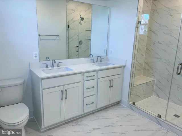 a spacious bathroom with a granite countertop toilet a sink and a mirror