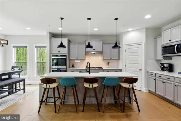 a kitchen with stainless steel appliances kitchen island granite countertop a table chairs sink and cabinets
