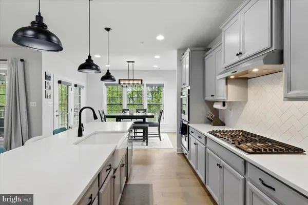 a kitchen with stainless steel appliances a stove a sink a kitchen island with a dining table and chairs