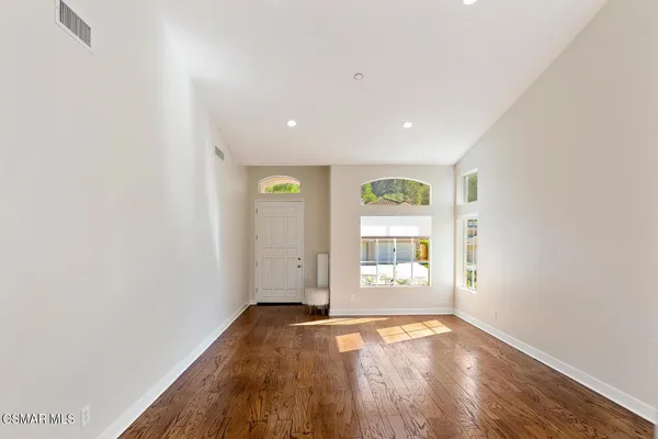 an empty room with wooden floor and windows