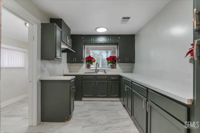 a kitchen with kitchen island granite countertop a sink cabinets and window