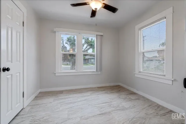 an empty room with chandelier fan and windows
