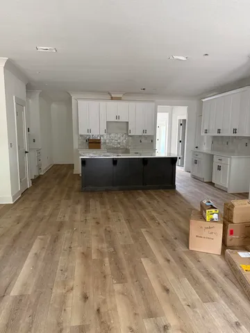a large white kitchen with kitchen island white cabinets and stainless steel appliances