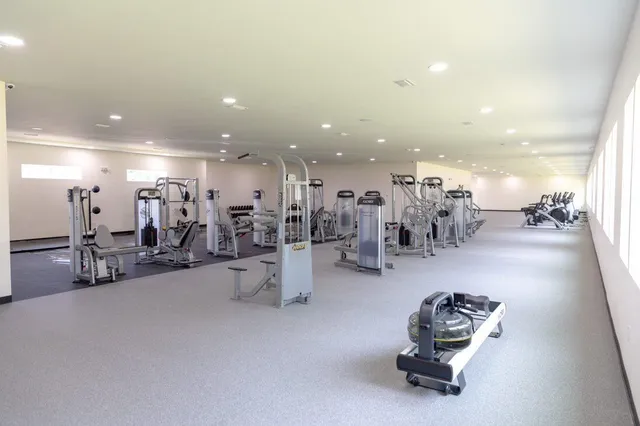 a gym room with gym equipment and a view of living room