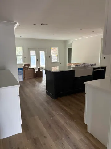 a living room with couches and kitchen view with wooden floor