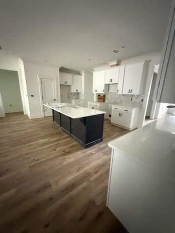 a large white kitchen with kitchen island a stove a sink dishwasher and cabinets with wooden floor