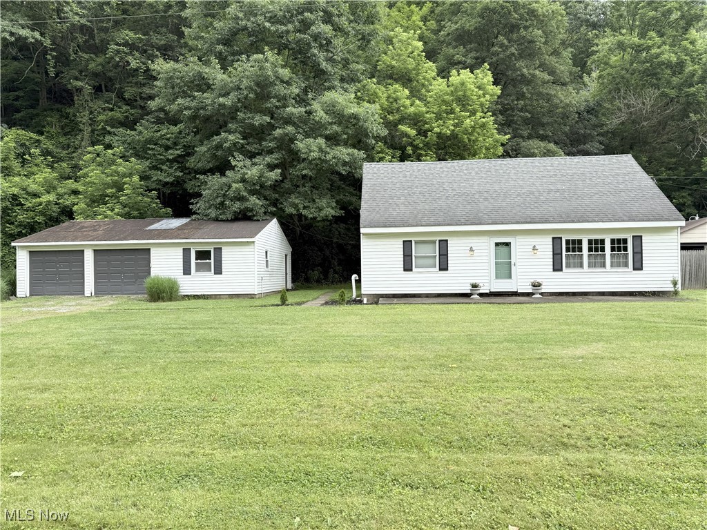 4901 Kings Creek Road Weirton, WV 26062 - Photo 1 of 28 View of front of home featuring a garage, an outbuilding, a front lawn, a shingled roof, and a view of trees
