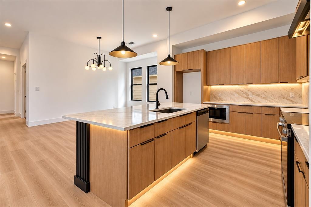1632 West Wintergreen Road Lancaster, TX 75134 - Photo 7 of 30 Kitchen island with a light-toned countertop, wood-finish cabinetry, stainless steel appliances, and integrated lighting