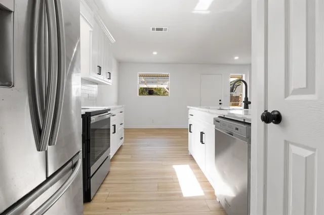 a kitchen with stainless steel appliances granite countertop a refrigerator a stove and a sink with wooden floor