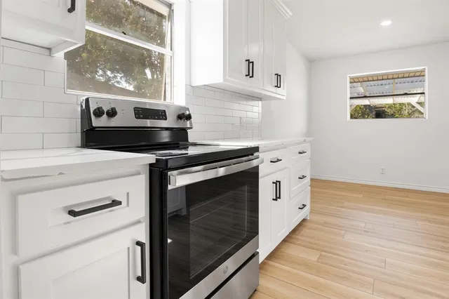 a kitchen with stainless steel appliances white cabinets and a window