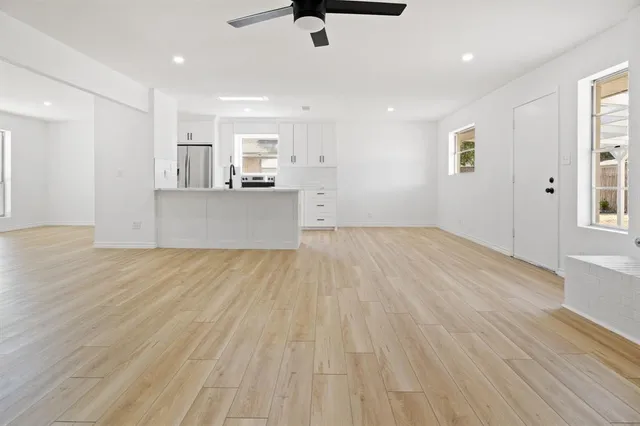 a view of kitchen and empty room with wooden floor