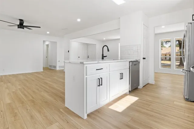 a large white kitchen with wooden floor and a sink