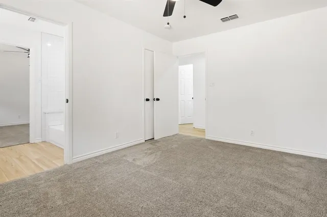 an empty room with windows and ceiling fan