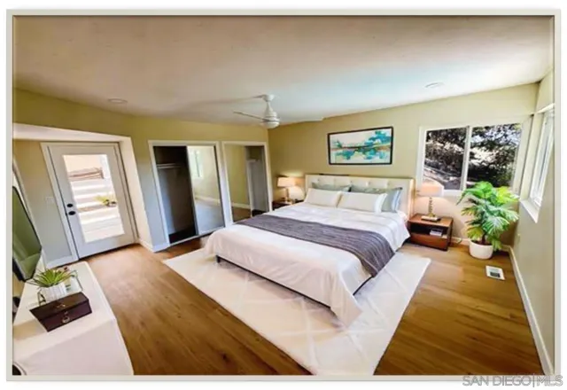 a bedroom with a bed wooden floor and view of living room