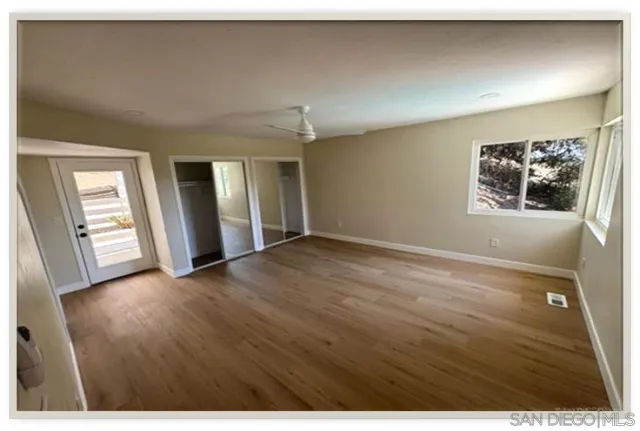 an empty room with wooden floor and windows