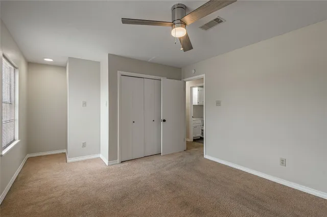an empty room with chandelier fan and windows