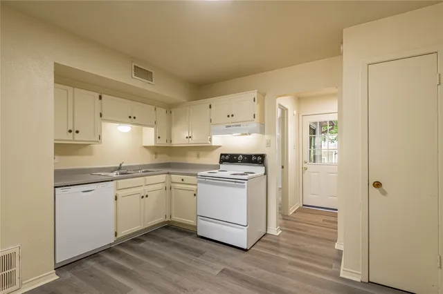 a kitchen with stainless steel appliances granite countertop a stove a sink and white cabinets