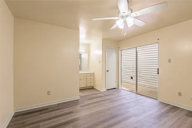 an empty room with wooden floor and ceiling fan