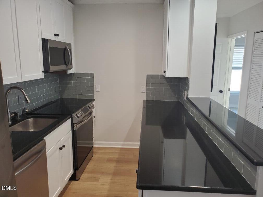 610 Hillsborough Street, Unit 205 Raleigh, NC 27603 - Photo 6 of 15 a kitchen with granite countertop stainless steel appliances sink stove microwave and cabinets