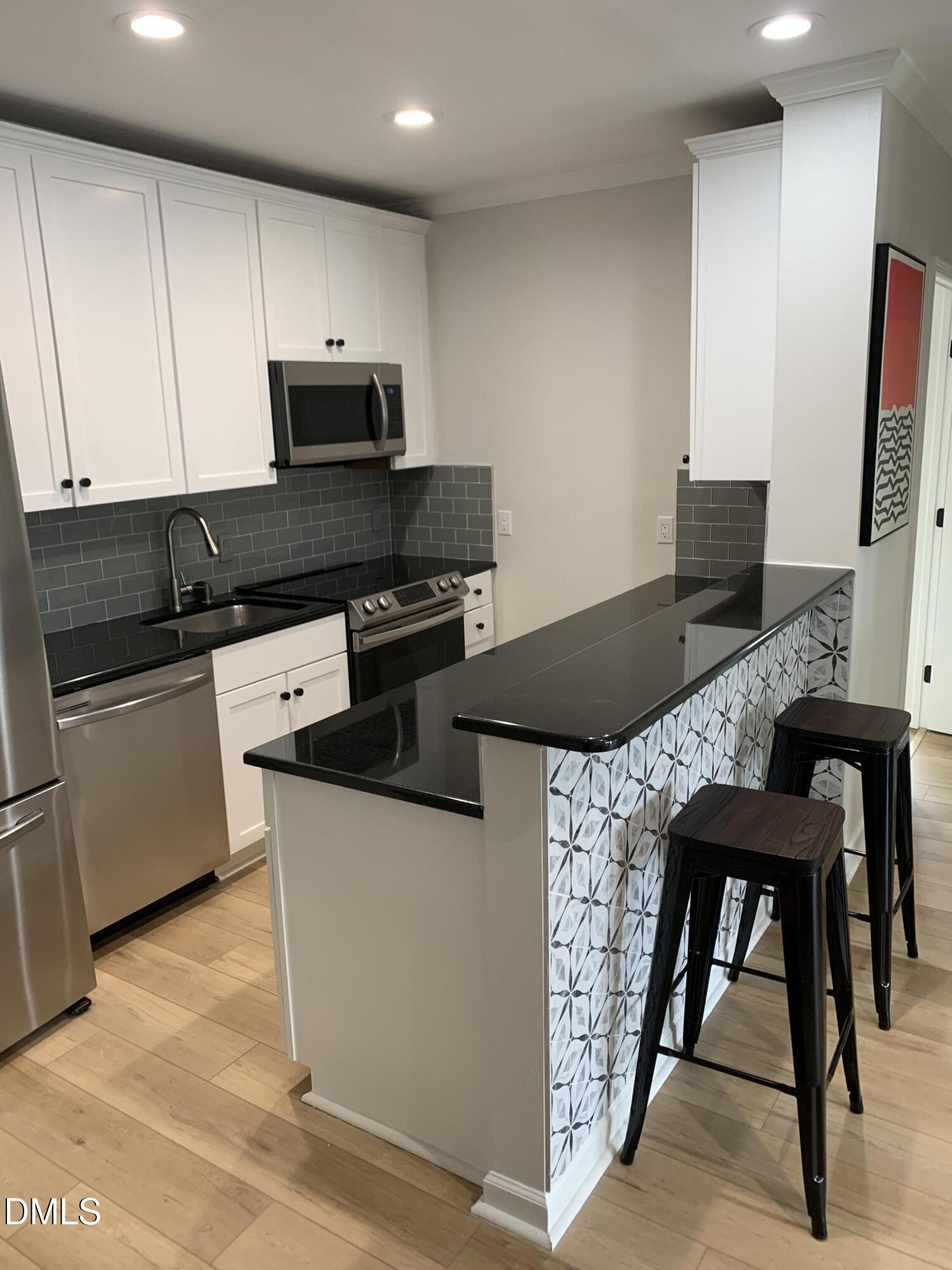 610 Hillsborough Street, Unit 205 Raleigh, NC 27603 - Photo 7 of 15 a kitchen with stainless steel appliances granite countertop a stove top oven a sink a counter space and cabinets