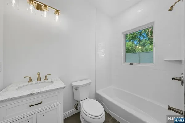 a bathroom with a granite countertop toilet a sink and a bathtub