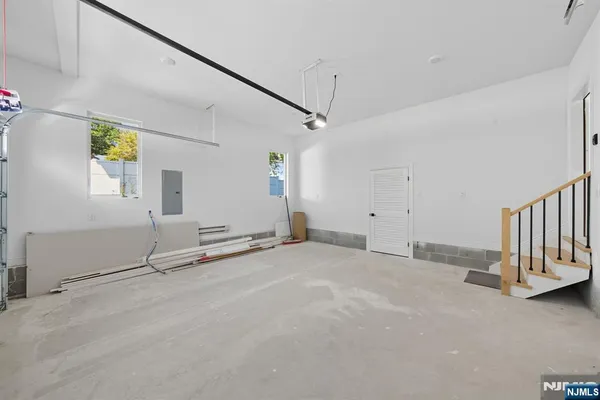a view of a white house with large windows and flower plants