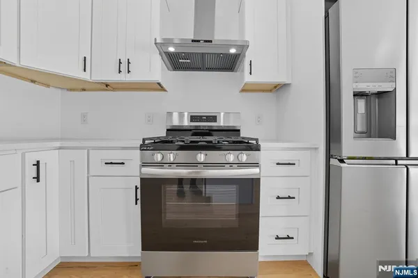 a kitchen with stainless steel appliances a stove and white cabinets