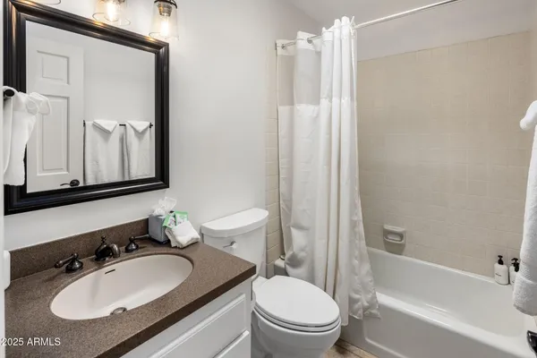 a bathroom with a granite countertop sink toilet a mirror and shower
