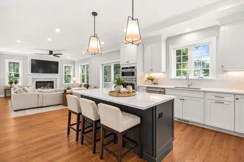 a kitchen with a dining table chairs cabinets wooden floor and appliances