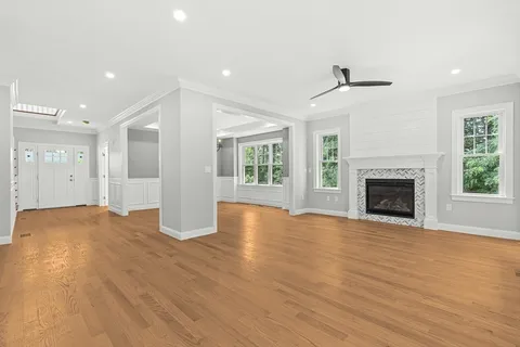 a view of an empty room with wooden floor fireplace and a window