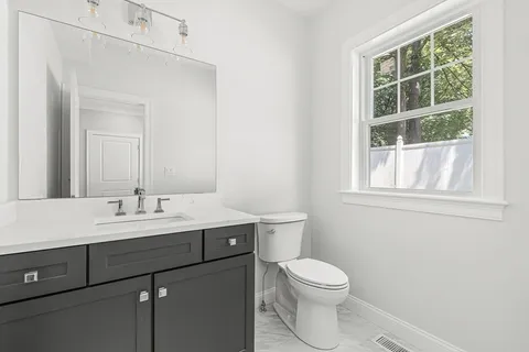 a bathroom with a toilet a sink a vanity and a window