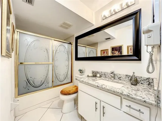 a bathroom with a granite countertop sink mirror vanity and toilet