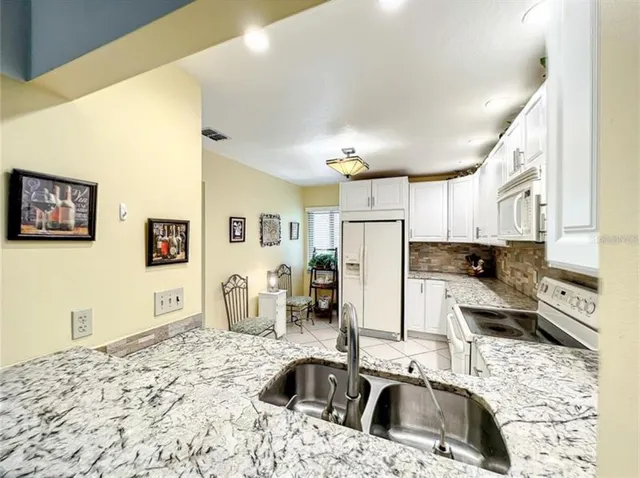 a kitchen that has a sink a refrigerator and a stove top oven