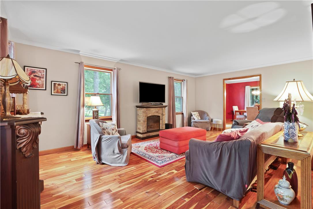 209 Remington Road East Stroudsburg, PA 18301 - Photo 6 of 41 Warm wood floors and a charming fireplace anchor this inviting living space, offering views of the surrounding greenery.