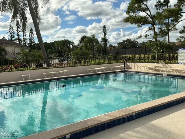 a view of swimming pool with a bench and trees