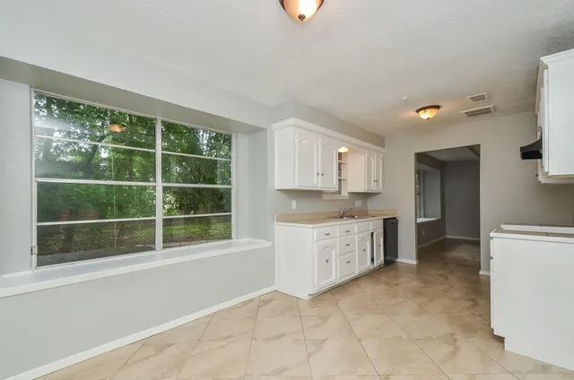 a large white kitchen with a sink cabinets and a window