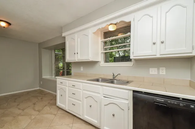 a kitchen with cabinets appliances a sink and a window