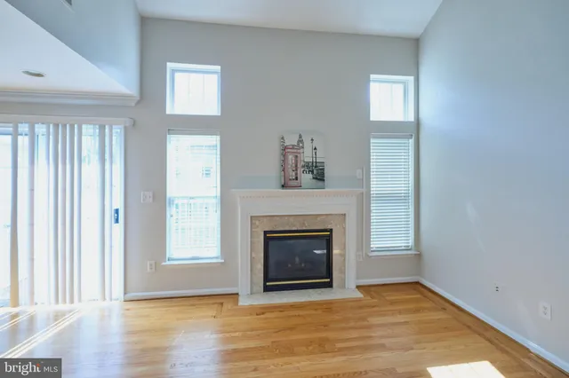 an empty room with wooden floor fireplace and windows
