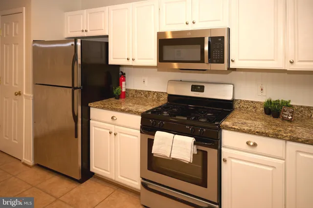 a kitchen with granite countertop white cabinets and stainless steel appliances