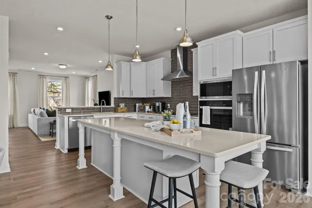 a kitchen with stainless steel appliances a table chairs refrigerator and microwave