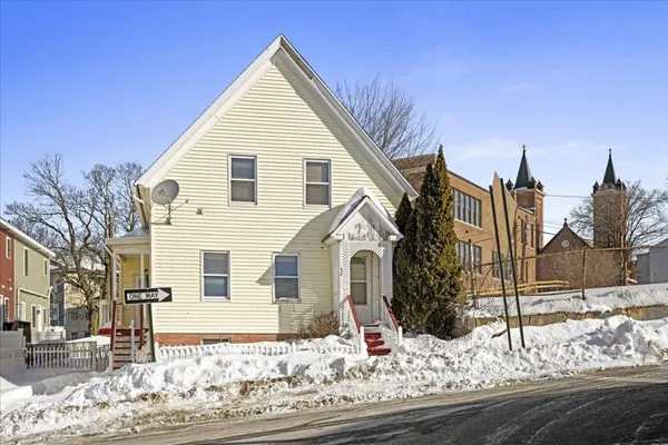 a view of a white house with wooden fence next to a road